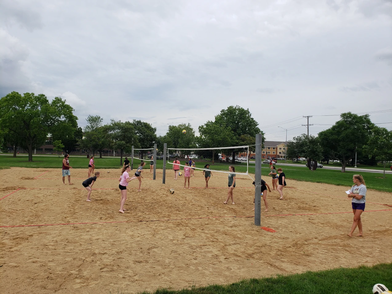 A wide angle shot of Edge athletes practicing their sand volleyball skills on a set of outdoor beach volleyball courts