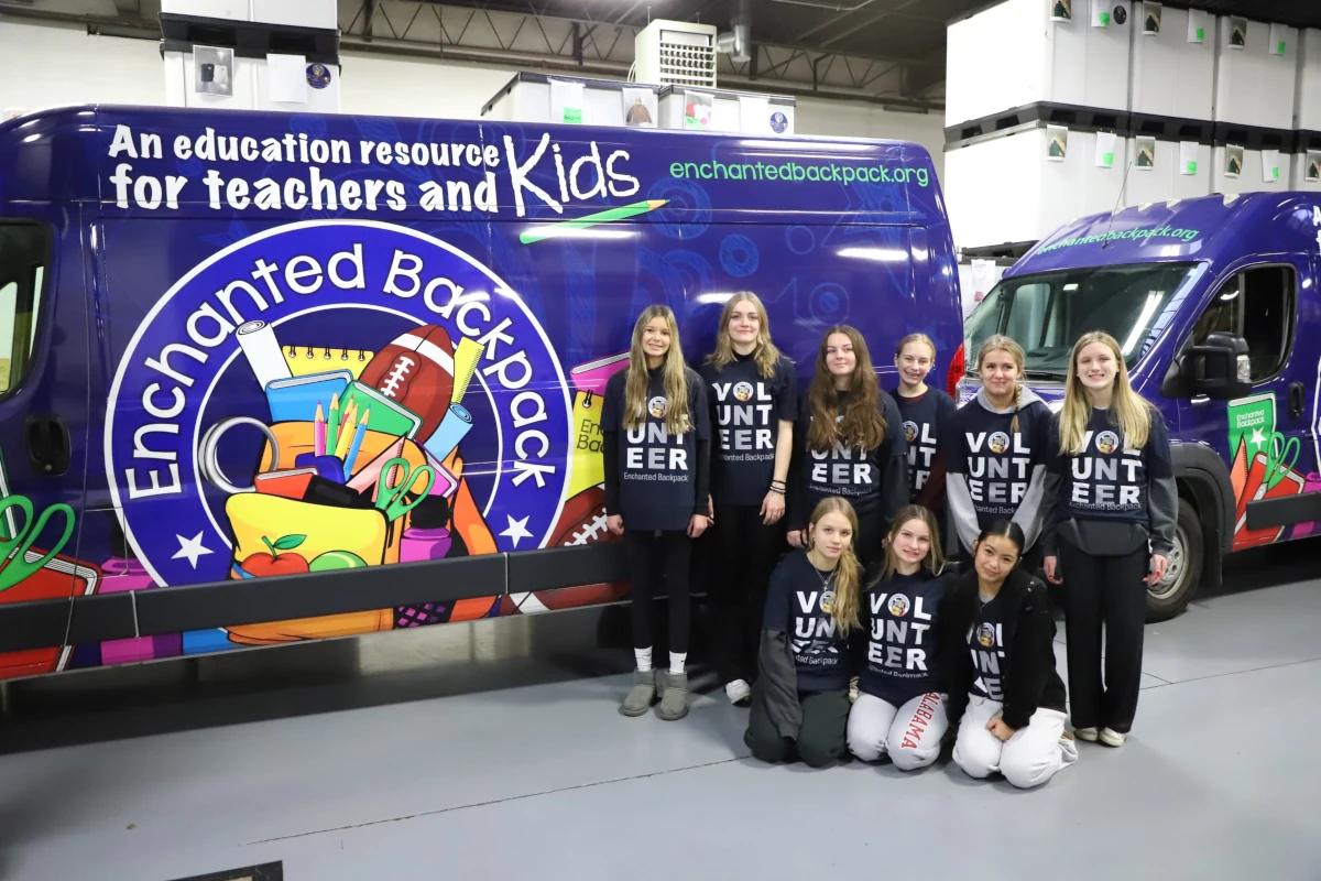 A group of Edge athletes posing in front of the Enchanted Backpack delivery van