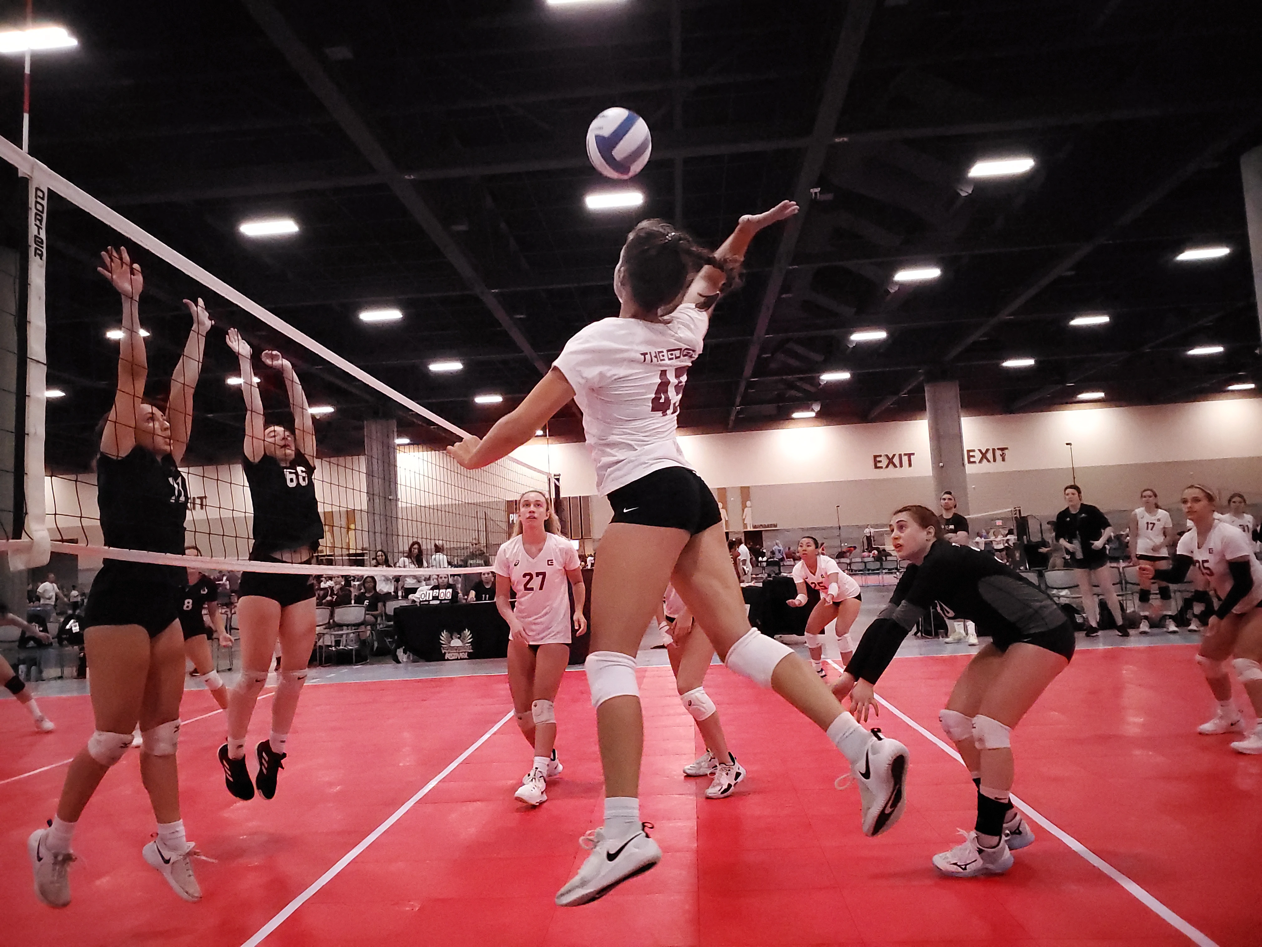 An Edge athlete mid-air primed and ready to hit a ball over an block