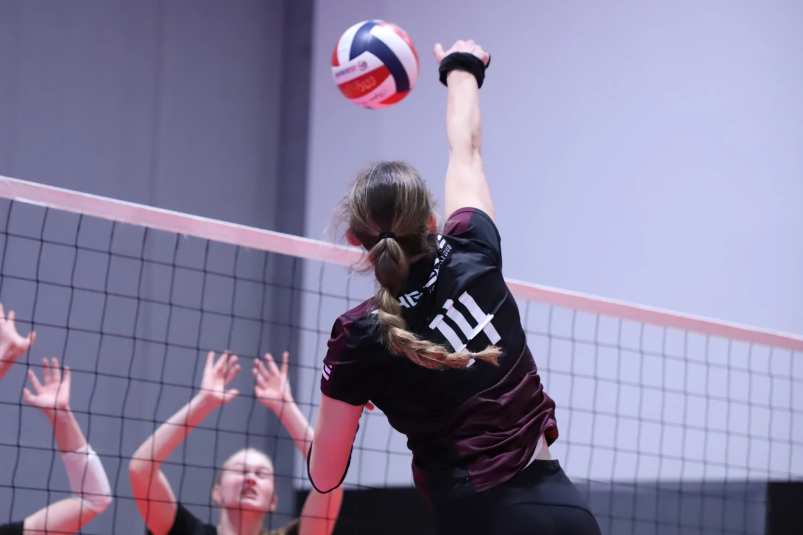 An Edge athlete mid-air primed and ready to hit a ball over an block