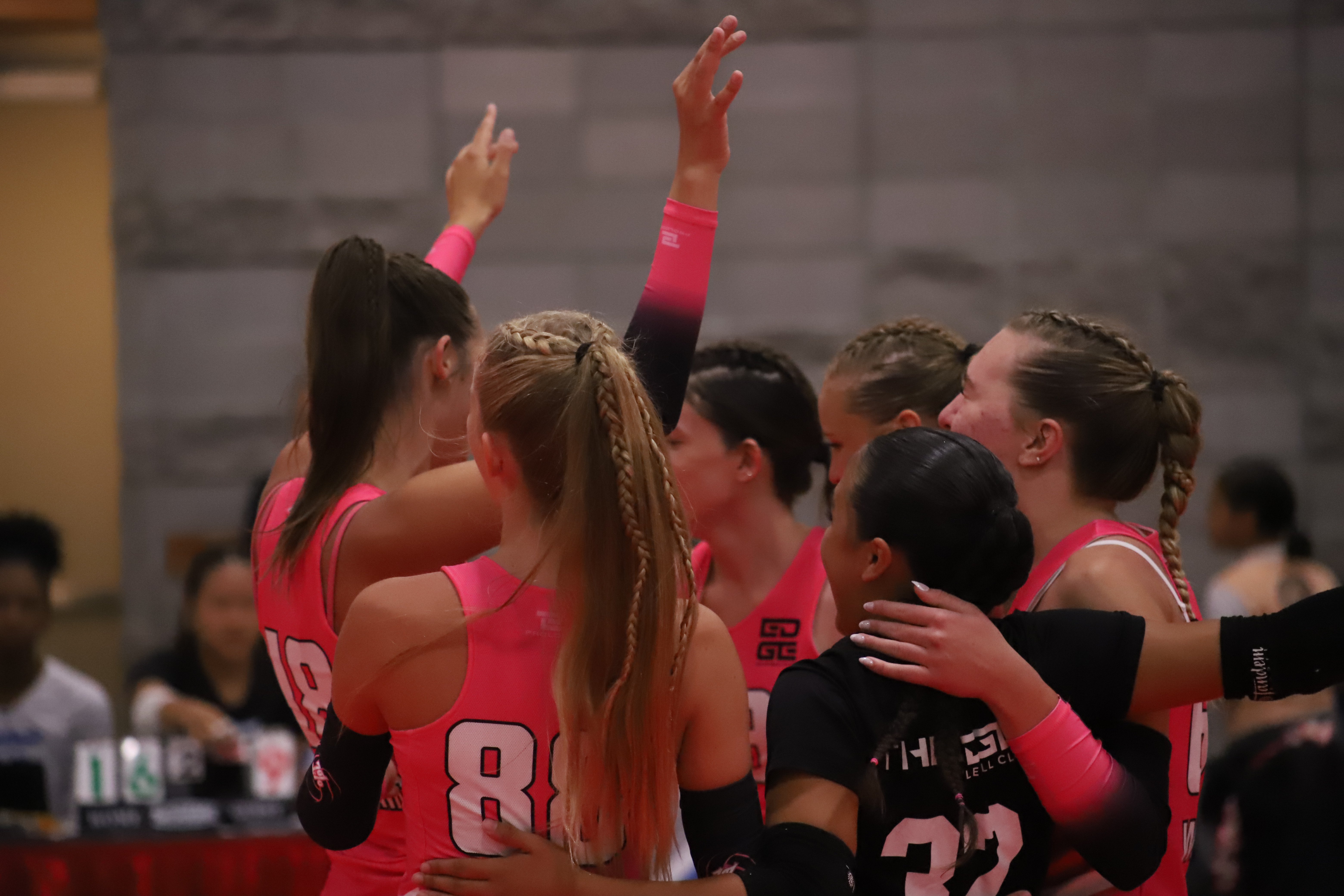 Edge athletes celebrating in a huddle in the middle of the court.