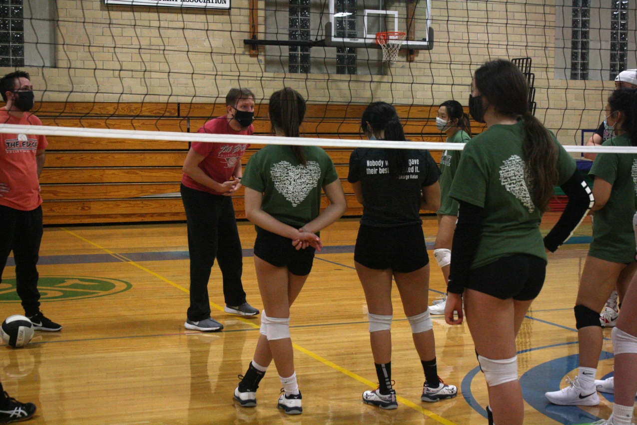 A group of Edge athletes surrounding a coach intently listening to instructions