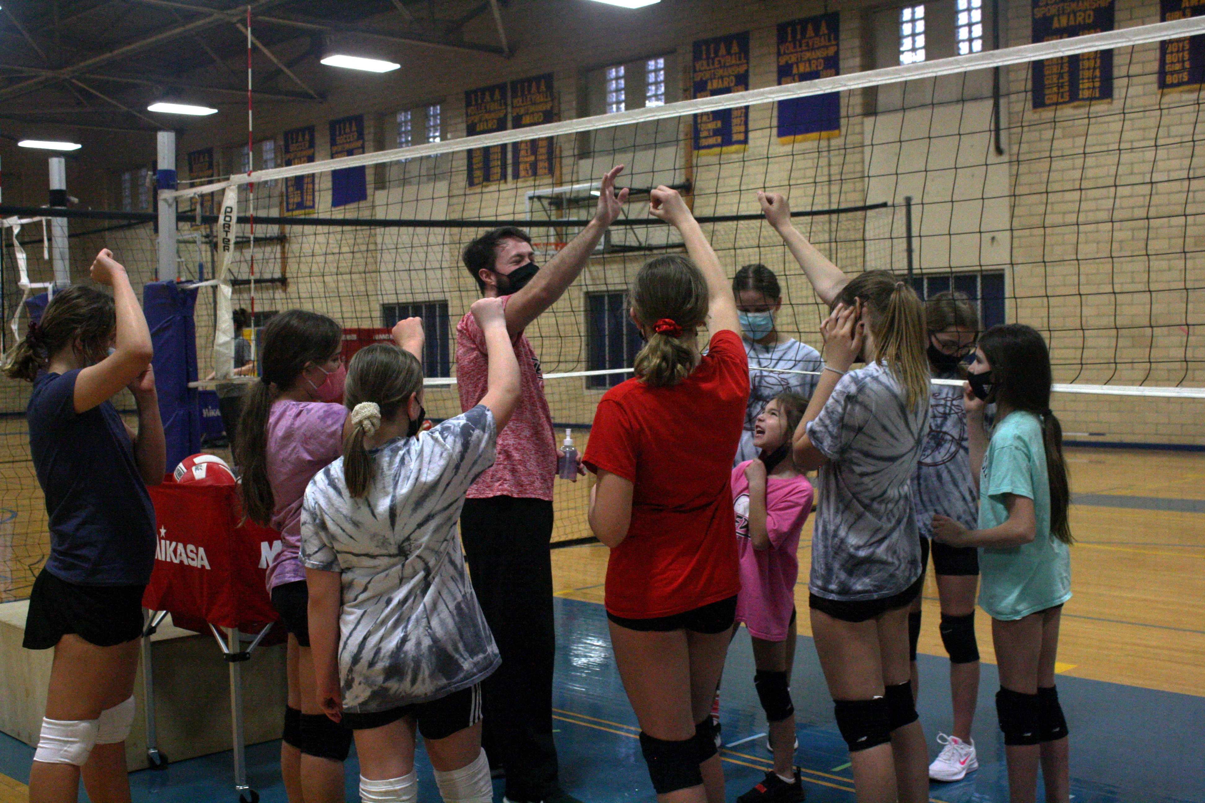 Group of Edge Volleyball athletes huddled around a coach.