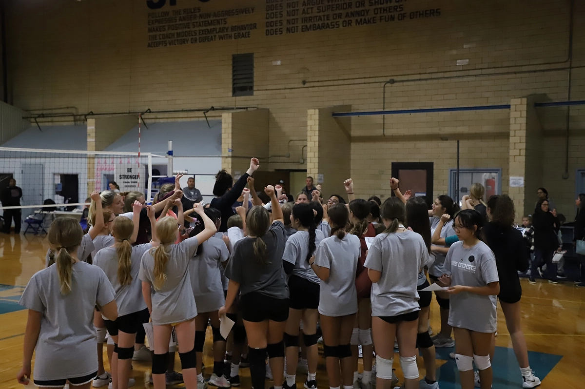 Group of Edge Volleyball athletes huddled around a coach.